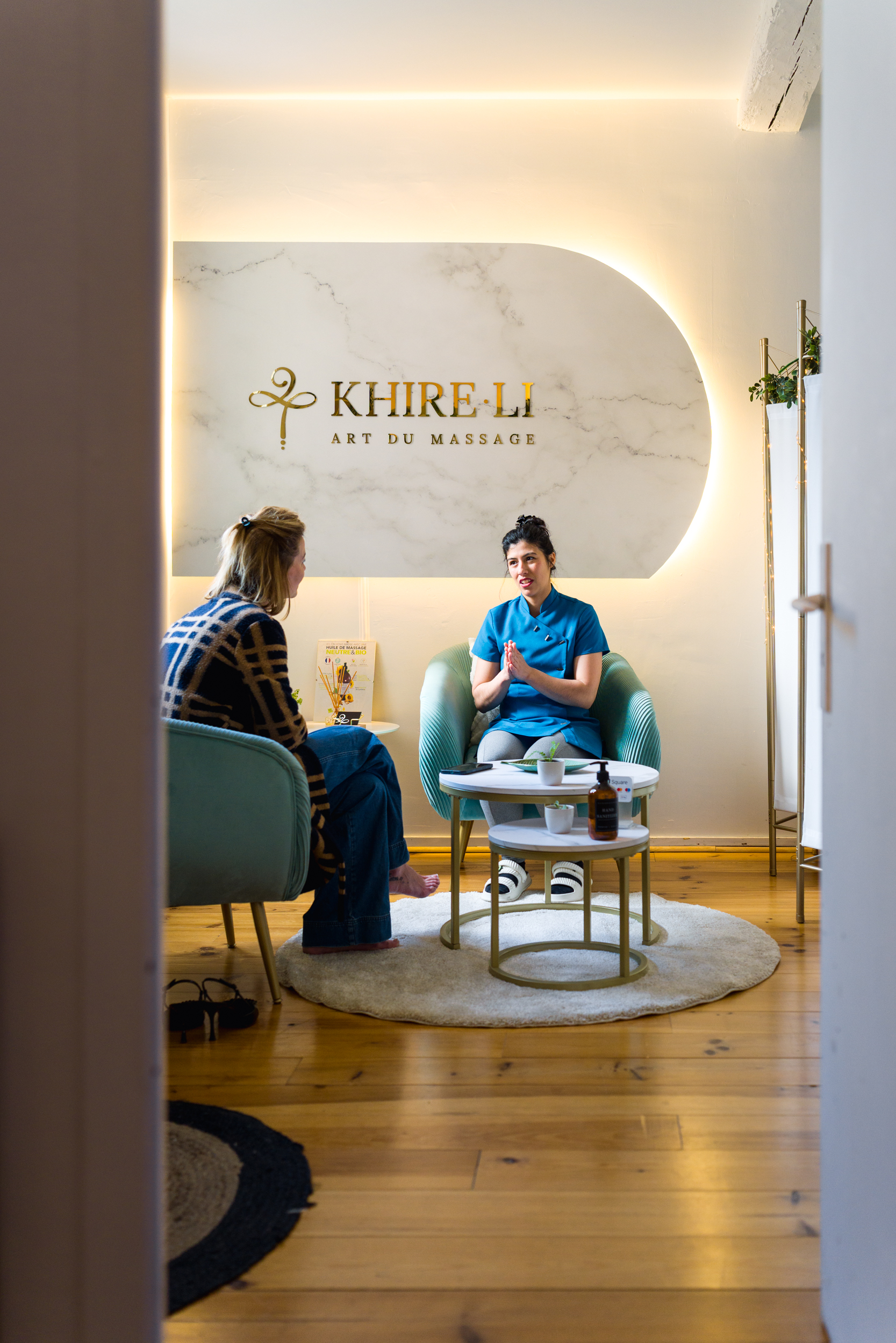 Table de massage dans le salon Khire·Li à Bordeaux — draps blancs, paravent doré, parquet bois